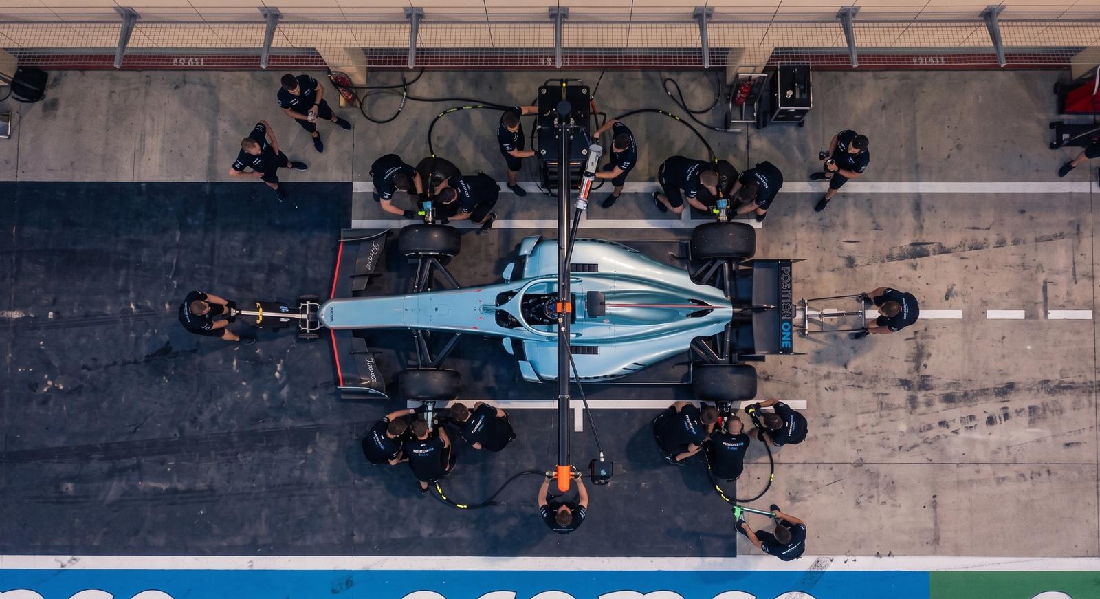 Vista de cima de um pit stop: a equipe da Position One trabalhando em volta do carro enquanto o piloto permanece no cockpit